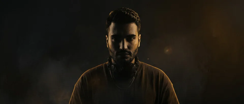 Divo Move in a dark, amber-lit portrait with headphones